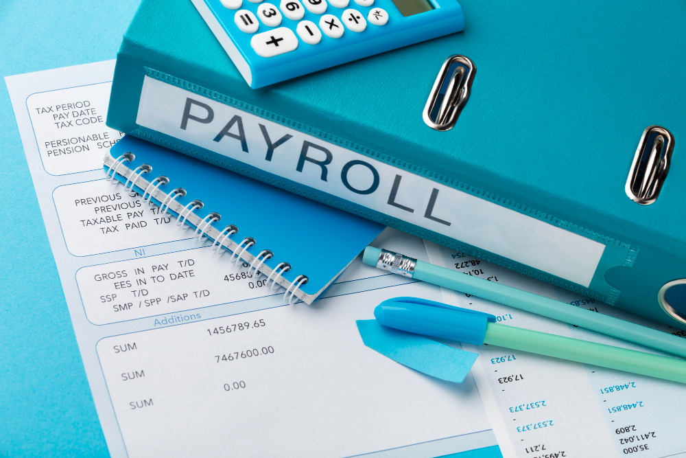 calculator, payroll documents with payslips on a table with the word payroll written on one of the documents