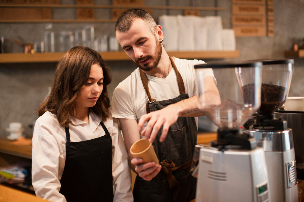 Man coffee bartender showing woman a cup with coffee machine